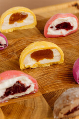 Assorted colorful mochi ice cream halves on wooden board, close-up view, studio lighting
