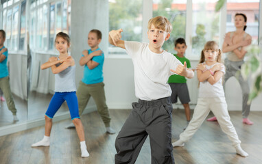 Obraz premium Active preteen boy practicing breakdance with other children and trainer in dancehall