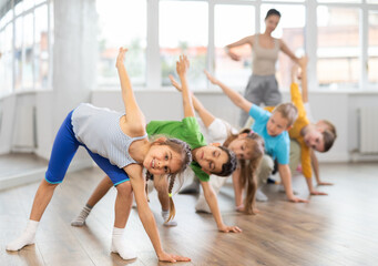 Children perform bends, stretches and squats to prepare their muscles and body. Students...