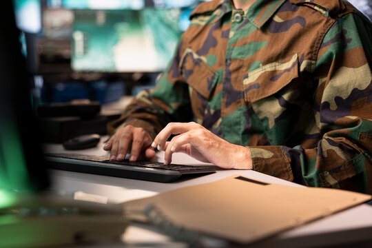 Air force combat control officer typing on keyboard, performing tactical level surveillance, close up. Military specialist using radar to search for potential assault zones, inputting coordinates - Powered by Adobe