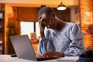 Overworked businesswoman in apartment, showing evening fatigue during remote work. Stressed and...