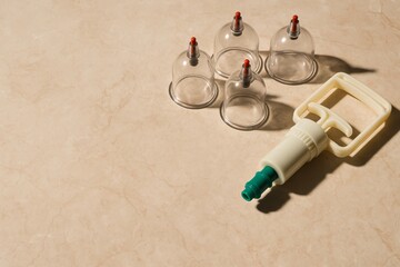 Essential cupping therapy tools and vacuum pump for alternative medicine. Recovery and wellness concept on textured background. Hijama, treatment according to the Sunnah.