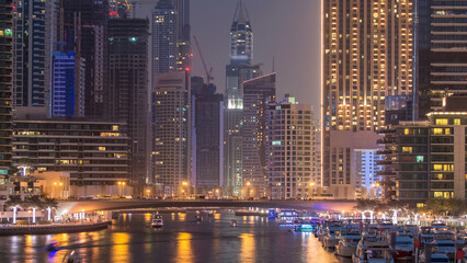 Evening Dubai marina city centre with floating vessels day to night timelapse