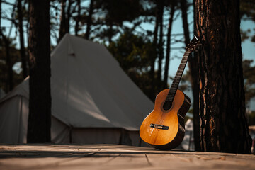 Acoustic guitar leaning against a tree, forest music scene with musical instrument