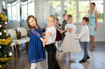 Little children in festive clothes dance the foxtrot dance while celebrating Christmas