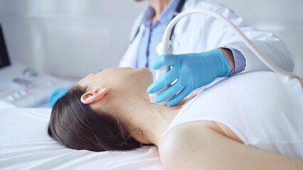 Doctor man wearing blue medical gloves is using ultrasound equipment on neck of female patient lying down for a medical examination