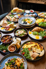 Assorted restaurant style breakfast table with eggs, pastries, salads, and fresh bread