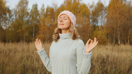 Calm relaxed young woman meditates, girl practicing doing yoga exercises outdoors, stress relief