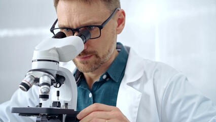 Man scientist with protective glasses using microscope in laboratory. Microbiology science concept