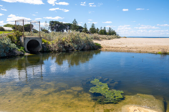Drain outlet with water flowing to sandy beach at Werribee South, Victoria, Australia. It carries water from inland areas (urban runoff, agricultural land, or stormwater) into the sea.