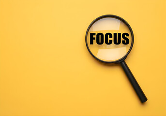A close-up shot features a magnifying glass centered over the word 'FOCUS', set against a vibrant yellow backdrop, highlighting the concept of concentration and clarity.