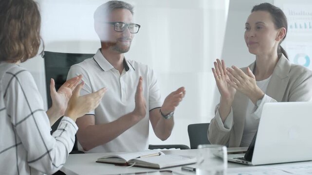 Professional team applauding, celebrating collaborative success and recognizing outstanding performance during corporate meeting, expressing shared workplace achievement