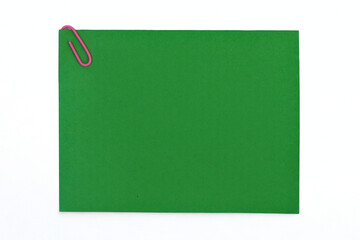 green note paper with paper clip attached to white background