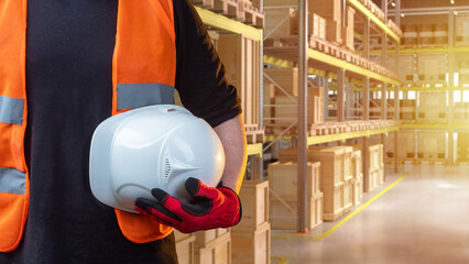 Man with helmet in hand standing in warehouse. Distribution center employee. Cropped contractor...