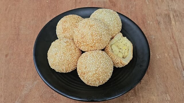 cookies in a bowl,Sesame balls or Onde onde or Jiandui or Kue moci or Kuih bom,a type of Chinese pastry,made from glutinous rice,coated with sesame seeds,filled with a filling usually beans,served wit