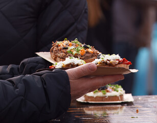 Freshly prepared open-faced sandwiches with meat, cheese and vegetables served on a paper tray at the Naplavka farmers market in Prague.