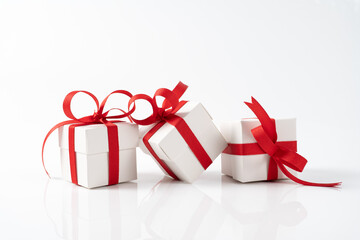 Three festive white gift boxes with red ribbon