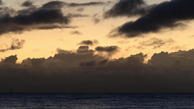 A timelapse shows a cloudy morning unfolding over the Coral Sea in Far North Queensland. Thick clouds drift slowly, then part to reveal warm sunlight breaking through the tropical sky and sea.