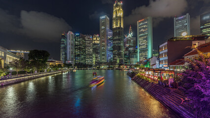 Fototapeta premium Singapore quay with tall skyscrapers in the central business district on Boat Quay day to night timelapse