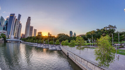 Sunset over Singapore skyscrapers skyline with white Anderson Bridge near esplanade park timelapse.