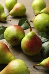 Fresh ripe pears and green leaves on wooden table, closeup