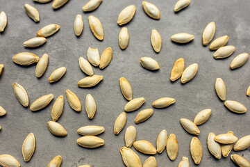 close-up of scattered roasted pumpkin seeds against a gray backdrop in a horizontal orientation