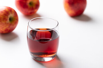 Glass of apple cider with red apple fruit on white background