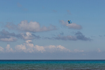 parasailing hobbie flying high in the air in middle of caribbean sea with blue sky at background in cancun mexico