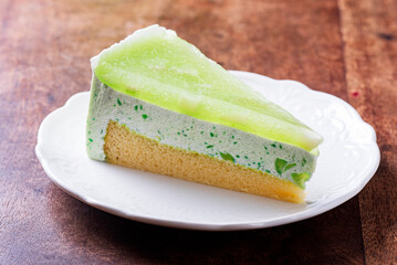 Pickled green mango mousse cake on white plate on wooden background.  