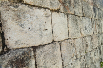 a texture of stone wall of ancient maya structure into Chichen Itza archaeological site