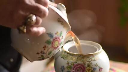 Hands pouring tea from decorated teapot - Powered by Adobe