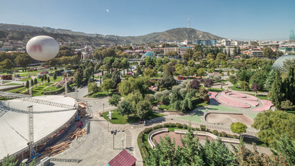 Aerial timelapse of Rike Park, a modern urban park in Tbilisi's Old Town with green trees and lawns. The Bridge of Peace in the background. Georgia © HyperlapsePro