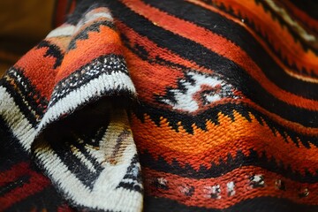 A close up of a hand woven wool blanket from Chile with intricate patterns and soft textures displayed on a neutral surface