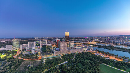 Fototapeta premium Aerial panoramic view over Vienna city with skyscrapers, historic buildings and a riverside promenade day to night timelapse in Austria.