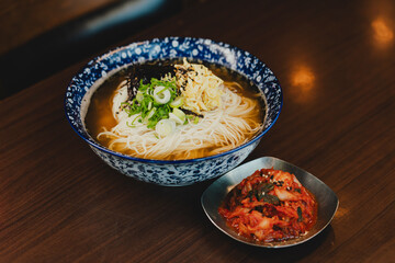Sizzling Korean BBQ pork belly (samgyeopsal) on tabletop charcoal grill with rising smoke and traditional banchan side dishes, close-up shot in cozy restaurant setting with copy space.