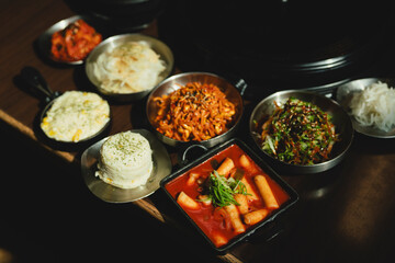 Sizzling Korean BBQ pork belly (samgyeopsal) on tabletop charcoal grill with rising smoke and...