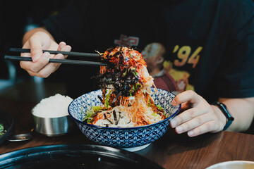 Sizzling Korean BBQ pork belly (samgyeopsal) on tabletop charcoal grill with rising smoke and traditional banchan side dishes, close-up shot in cozy restaurant setting with copy space.