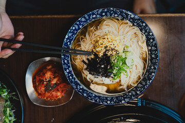 Grilled Korean beef short ribs (galbi) with caramelized edges on hot grill, served with lettuce wraps and kimchi, authentic Korean barbecue dining experience, overhead view.