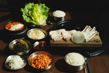 Grilled Korean beef short ribs (galbi) with caramelized edges on hot grill, served with lettuce wraps and kimchi, authentic Korean barbecue dining experience, overhead view.