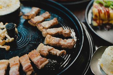 Grilled Korean beef short ribs (galbi) with caramelized edges on hot grill, served with lettuce wraps and kimchi, authentic Korean barbecue dining experience, overhead view.
