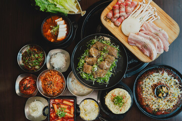Grilled Korean beef short ribs (galbi) with caramelized edges on hot grill, served with lettuce wraps and kimchi, authentic Korean barbecue dining experience, overhead view.