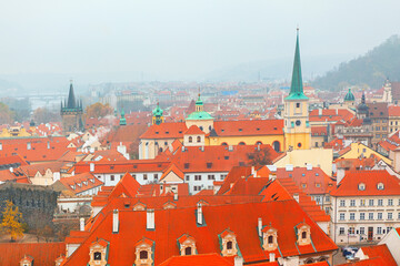 Obraz premium Tiled rooftops stretch across Prague historic cityscape under a cloudy sky. A timeless European panorama capturing architectural charm and old-world atmosphere from above