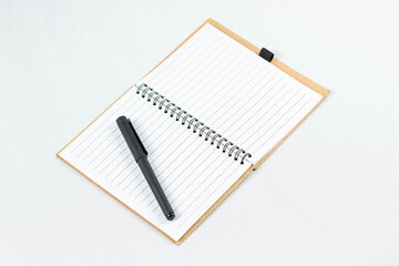a blanked notebook with a white lined sheets and a black pen over the left sheet and a white background