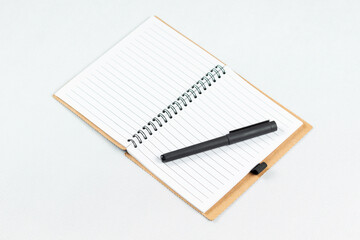 a blanked notebook with a white lined sheets and a black pen over the right sheet and a white background