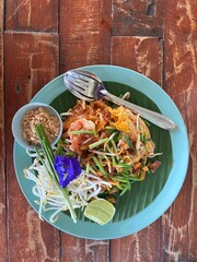 Pad Thai with seafood in a green plate on the table