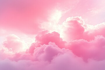 Fototapeta premium Fluffy clouds glowing in soft pink and purple hues with light shining through a dreamy sky