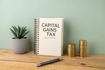 Capital gains tax concept. Tax levied on the profit earned from the sale of an asset. Business and finance. Notebook and coins and pen on the table.