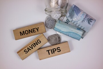 An artistic depiction of a money-saving concept, showcasing wooden blocks, coins, and currency...