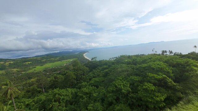 Forward FPV glide over forested hills at Bato ni Ningning reveals Long Beach and the San Vicente shoreline beneath wide afternoon clouds.