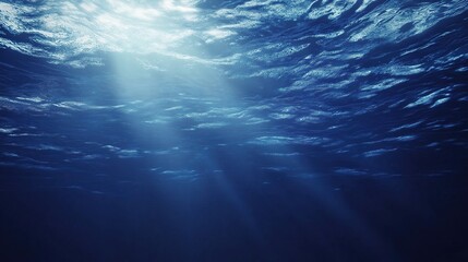 Sunlight streams through ocean waves, creating a mesmerizing play of light and shadow in deep blue waters.